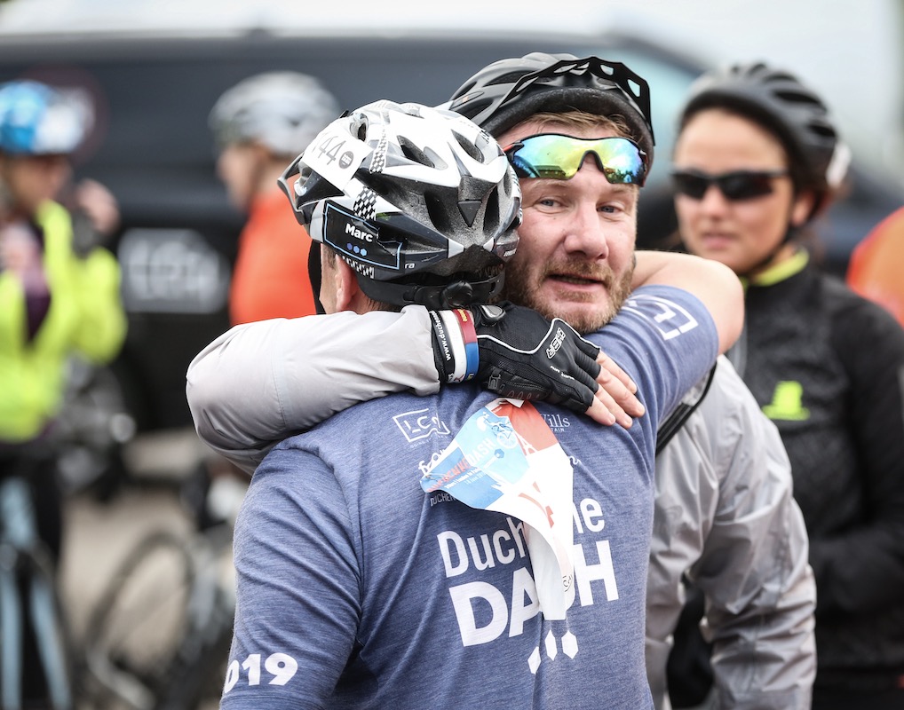 Two Duchenne Dash cyclists hugging