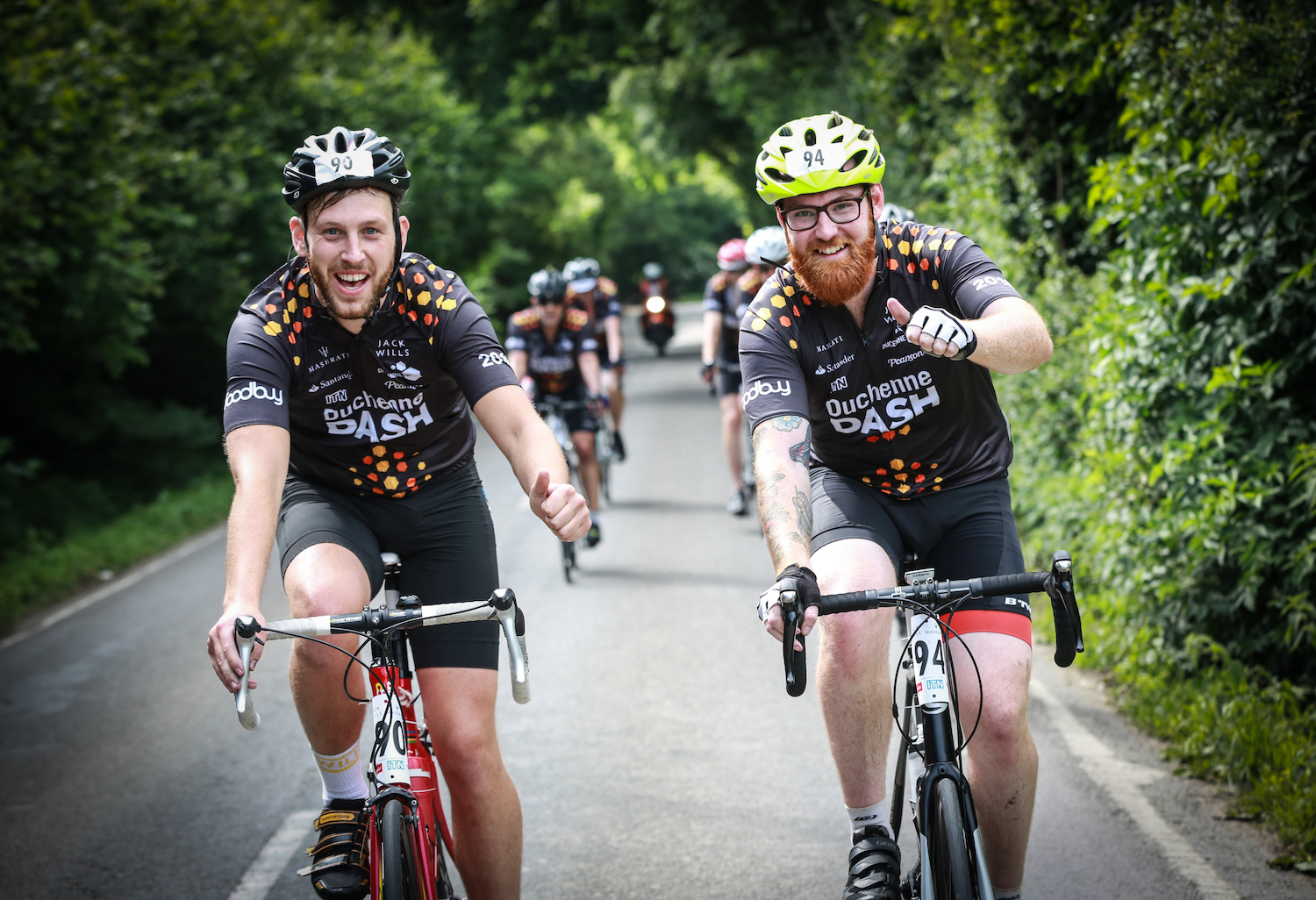Two Duchenne Dash cyclists on the road with their thumbs up
